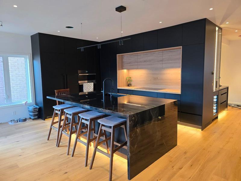 Matte black modern kitchen with island seating and light oak flooring in Toronto