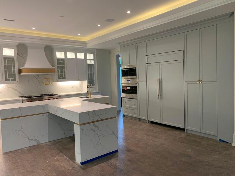 Custom white kitchen with quartz waterfall island and brass hardware in Newmarket
